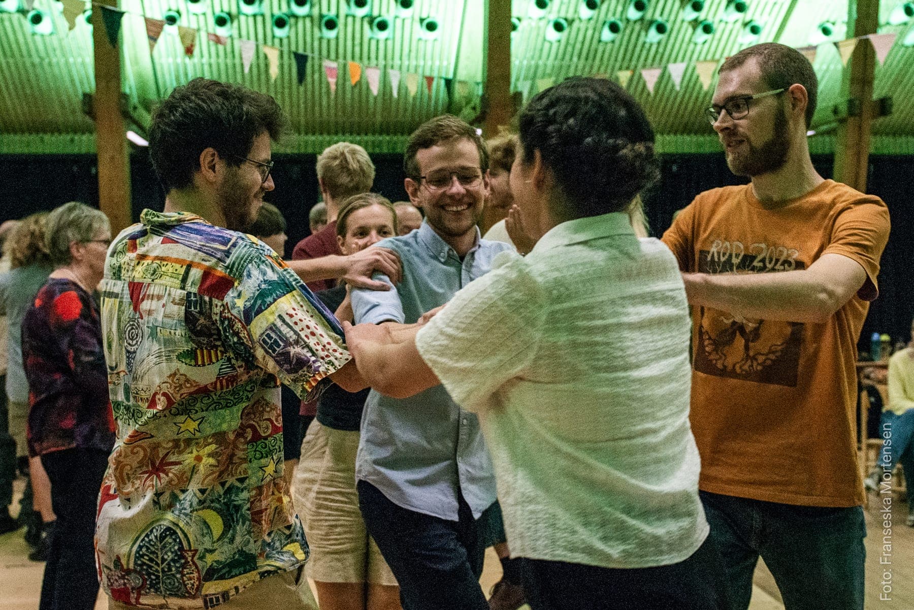 Festivalgæster smiler og danser sammen i en rundkreds